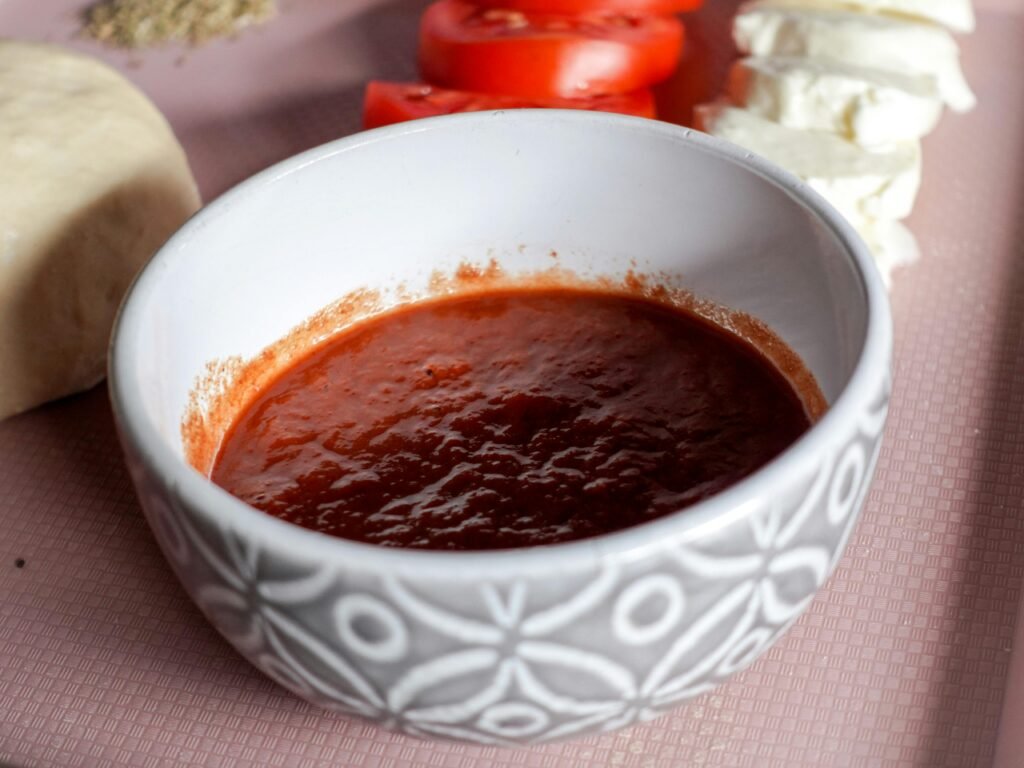 A bowl of tomato sauce surrounded by mozzarella cheese and sliced tomatoes, perfect for Italian cooking.