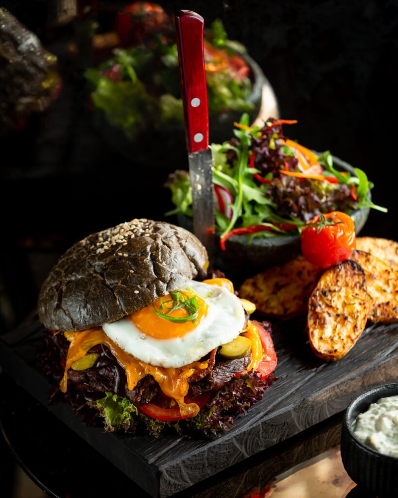 burger black bun with fried egg potatoes